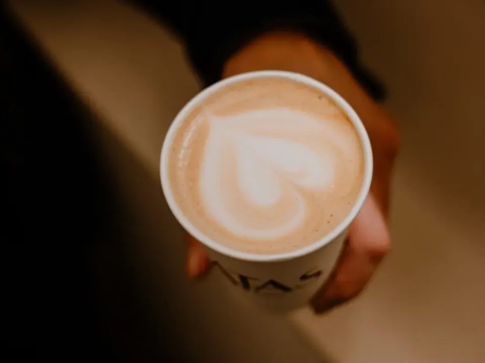 Un latte con dibujo en la espuma, recién servido en la barra de CATAS