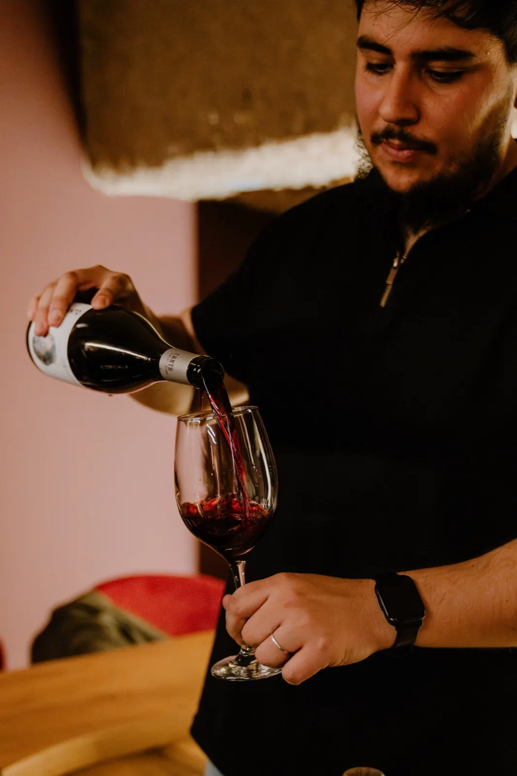 Un integrante del equipo sirve vino tinto en una copa
